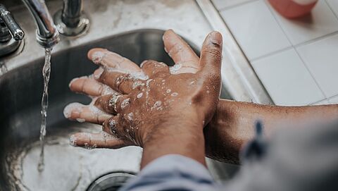 Hier staat een foto van een persoon die handen wast