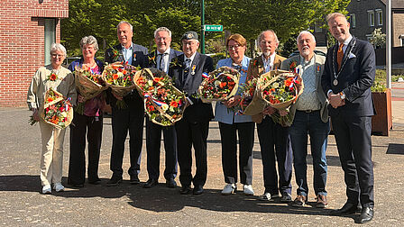 Foto van de acht gedecoreerden met de burgemeester